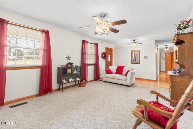 living room with carpet flooring, ceiling fan, and a textured ceiling