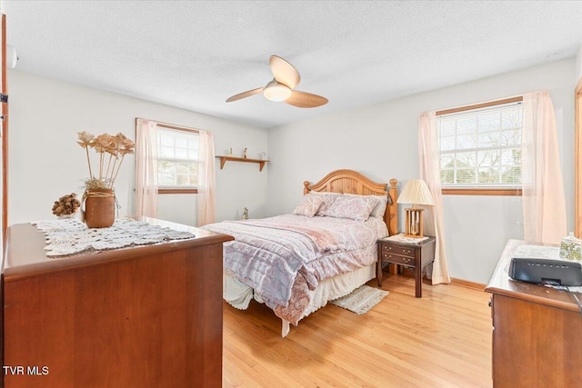 bedroom featuring ceiling fan, light wood-type flooring, and a textured ceiling