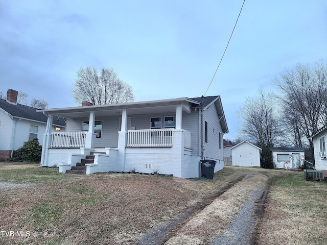 bungalow with a porch, an outbuilding, and central air condition unit