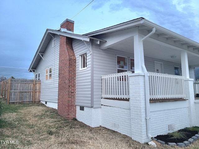 view of side of home with crawl space, a chimney, a carport, and fence