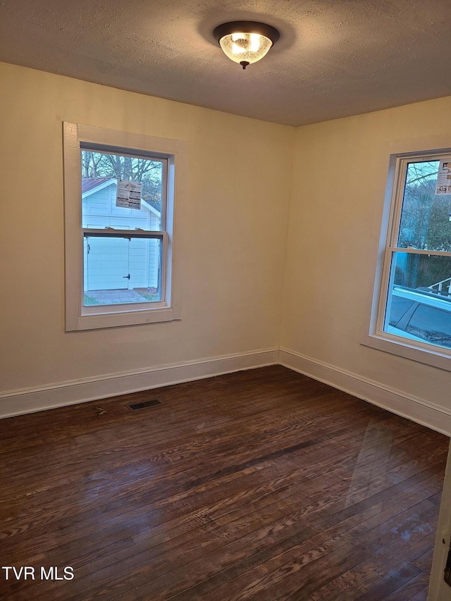 unfurnished room with a textured ceiling and dark wood-type flooring