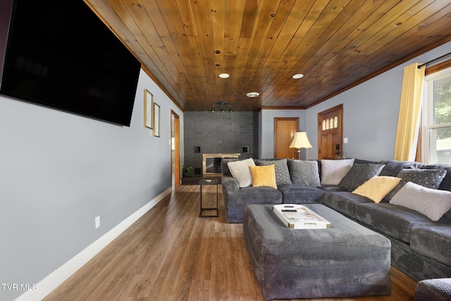 living room featuring wood-type flooring, a brick fireplace, crown molding, and wood ceiling