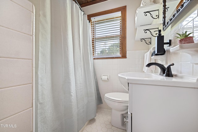 bathroom featuring tile patterned floors, vanity, toilet, and tile walls