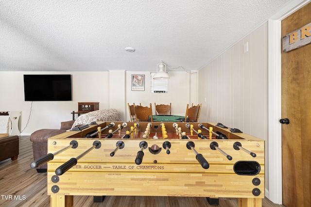 recreation room featuring a textured ceiling and hardwood / wood-style flooring