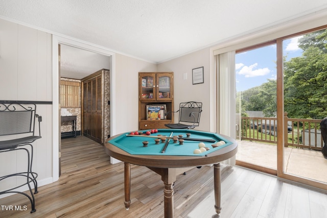 game room with a textured ceiling, light hardwood / wood-style floors, and crown molding