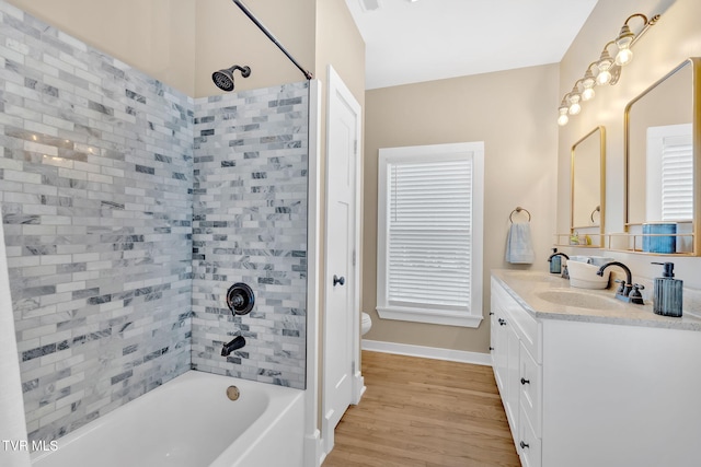 full bathroom featuring vanity, hardwood / wood-style floors, tiled shower / bath combo, and toilet