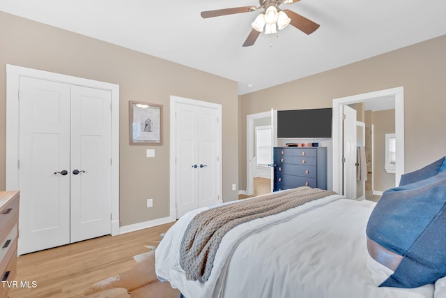 bedroom featuring multiple closets, ensuite bathroom, ceiling fan, and light hardwood / wood-style floors