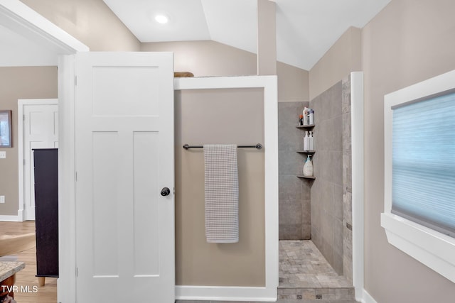 bathroom featuring lofted ceiling and tiled shower