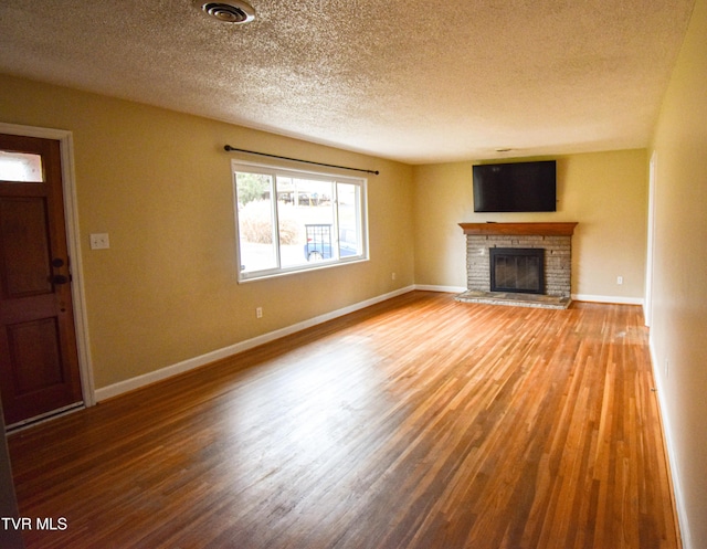 unfurnished living room featuring a fireplace, a textured ceiling, and hardwood / wood-style flooring