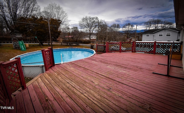 view of swimming pool featuring a playground and a deck