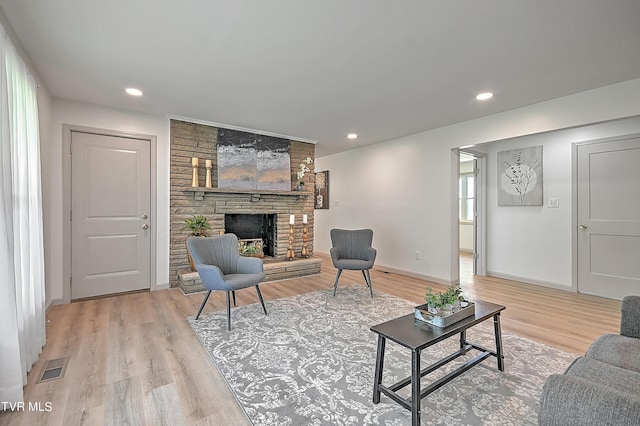 living room with a stone fireplace and light wood-type flooring