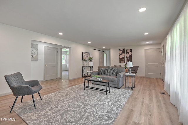 living room with a barn door and light hardwood / wood-style floors