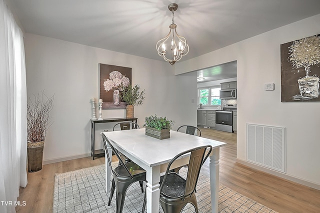 dining space with a chandelier and light hardwood / wood-style flooring