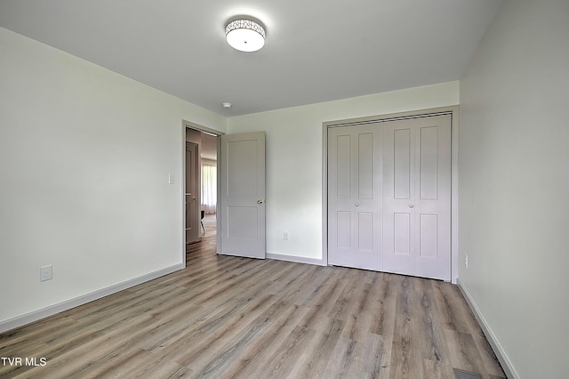 unfurnished bedroom with light hardwood / wood-style flooring and a closet