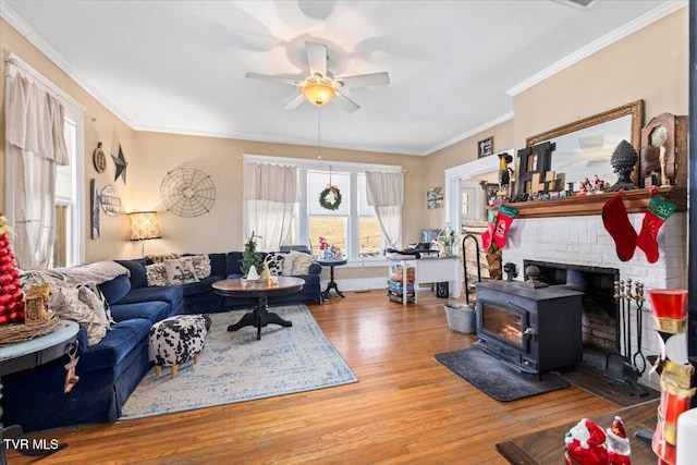 living room with a wood stove, ceiling fan, ornamental molding, and hardwood / wood-style flooring