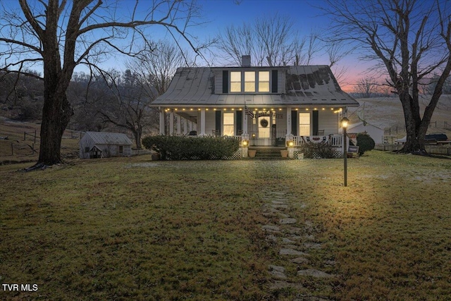 view of front of home with an outbuilding, a porch, and a yard