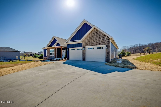 craftsman-style house featuring driveway, an attached garage, central air condition unit, board and batten siding, and brick siding