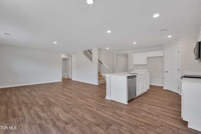 kitchen with light wood-type flooring, stainless steel appliances, a kitchen island with sink, sink, and white cabinets