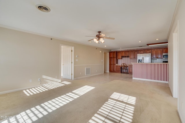 unfurnished living room featuring ceiling fan, light colored carpet, and ornamental molding