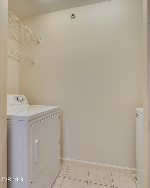 clothes washing area with washer and dryer and light tile patterned floors