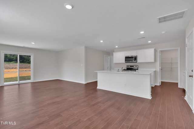 kitchen with dark hardwood / wood-style flooring, white cabinetry, stainless steel appliances, and an island with sink