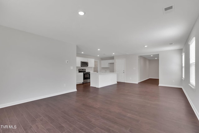 unfurnished living room featuring dark wood-type flooring, recessed lighting, visible vents, and baseboards