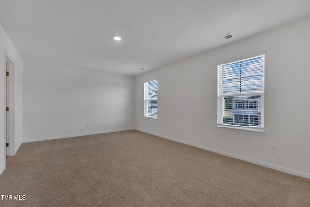 unfurnished room with baseboards, visible vents, and light colored carpet