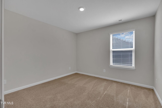 spare room featuring baseboards, visible vents, and carpet flooring