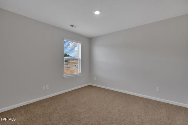 carpeted spare room with visible vents and baseboards