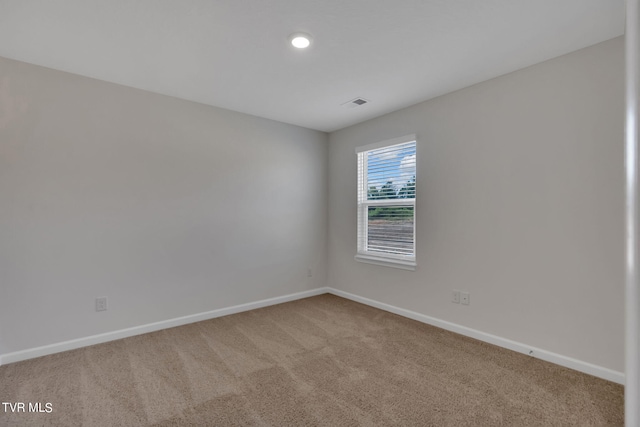 empty room with carpet, visible vents, and baseboards