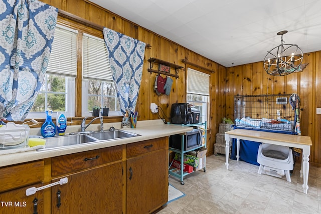 kitchen featuring an inviting chandelier, sink, pendant lighting, and wooden walls