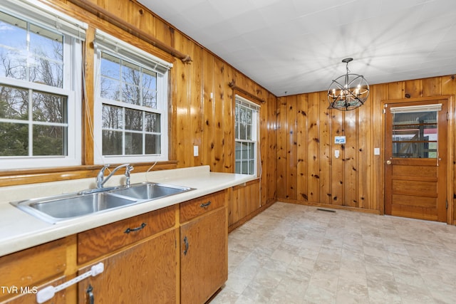 kitchen featuring pendant lighting, sink, plenty of natural light, and wood walls