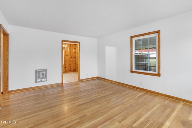 unfurnished room featuring heating unit and light hardwood / wood-style flooring