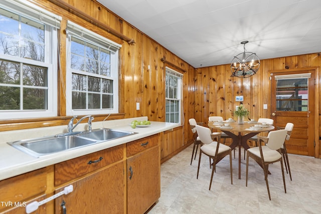 kitchen featuring sink, a notable chandelier, wooden walls, and decorative light fixtures