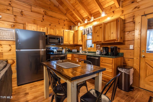 kitchen with appliances with stainless steel finishes, light hardwood / wood-style flooring, wooden ceiling, vaulted ceiling with beams, and wood walls