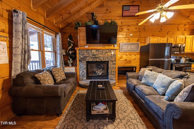 living room featuring hardwood / wood-style floors, wood walls, lofted ceiling with beams, a stone fireplace, and wood ceiling