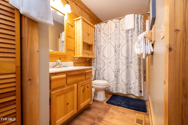 bathroom with a shower with shower curtain, hardwood / wood-style floors, vanity, and toilet