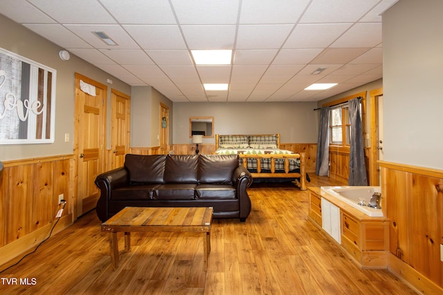 living room featuring light wood-type flooring and a paneled ceiling