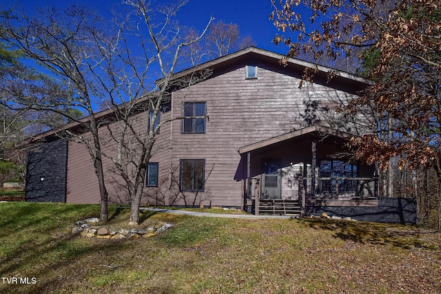 rear view of house featuring a lawn and a porch