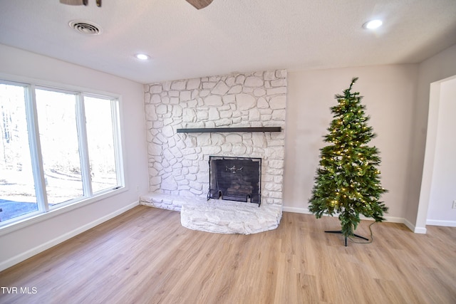 unfurnished living room with a fireplace, a textured ceiling, and light wood-type flooring