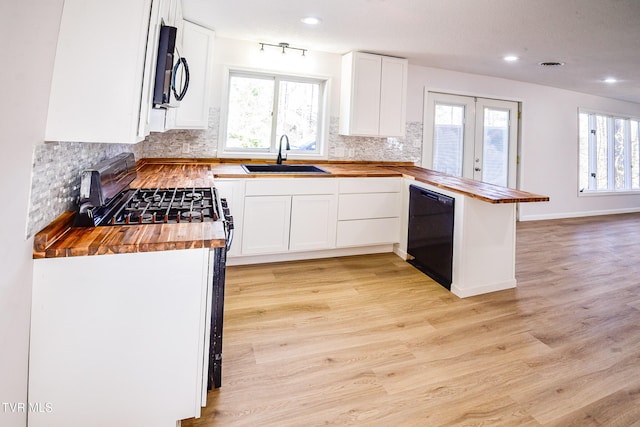 kitchen featuring white cabinetry, sink, black dishwasher, butcher block countertops, and kitchen peninsula