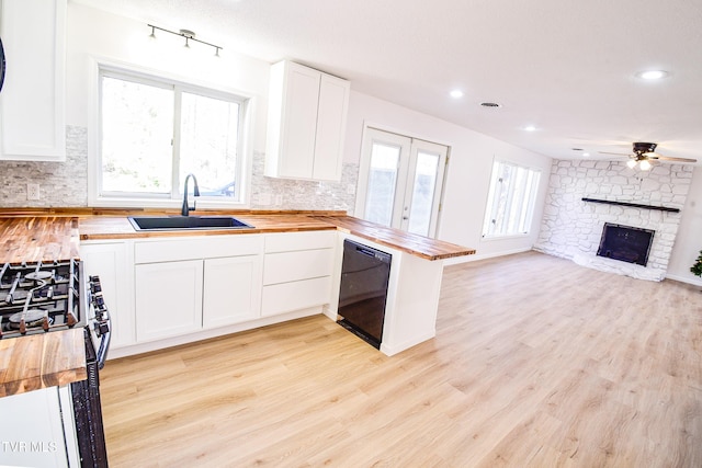 kitchen featuring white cabinets, sink, black dishwasher, butcher block countertops, and kitchen peninsula