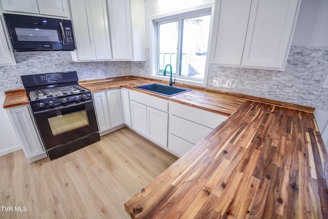 kitchen with wooden counters, black appliances, white cabinets, sink, and light wood-type flooring