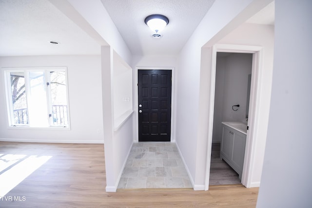 entryway with light hardwood / wood-style flooring and a textured ceiling