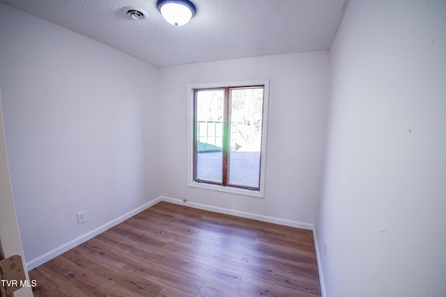 empty room with wood-type flooring and a textured ceiling