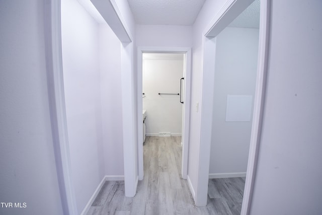 hallway featuring light hardwood / wood-style flooring and a textured ceiling