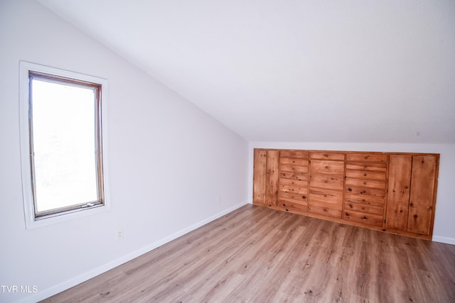 additional living space with light hardwood / wood-style flooring and vaulted ceiling