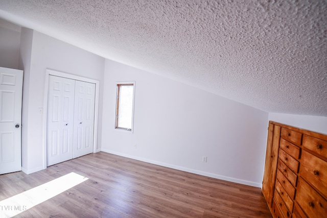 bonus room featuring hardwood / wood-style floors, a textured ceiling, and vaulted ceiling