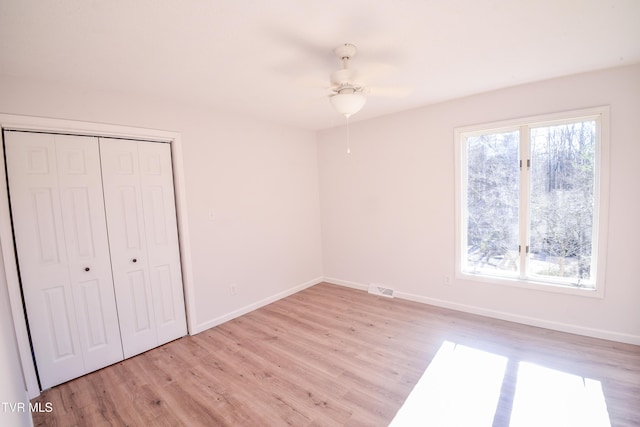 unfurnished bedroom featuring ceiling fan, a closet, and light wood-type flooring