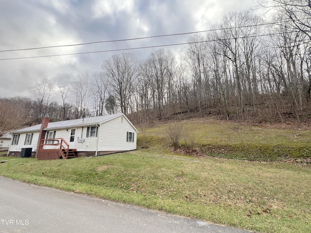 view of front of home with central AC unit and a front lawn